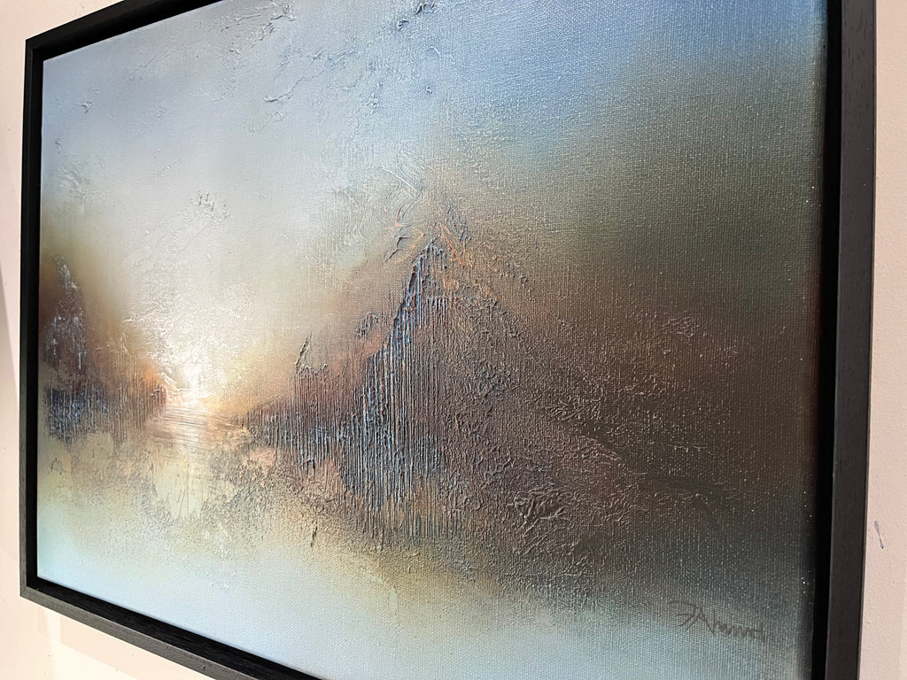 A framed abstract landscape painting with textured brushstrokes in muted blue, gray, brown, and cream tones, shown hanging on a light wall.