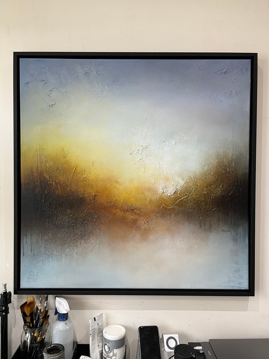 My Light framed abstract painting hanging above a desk, with blue, grey, gold and brown tones