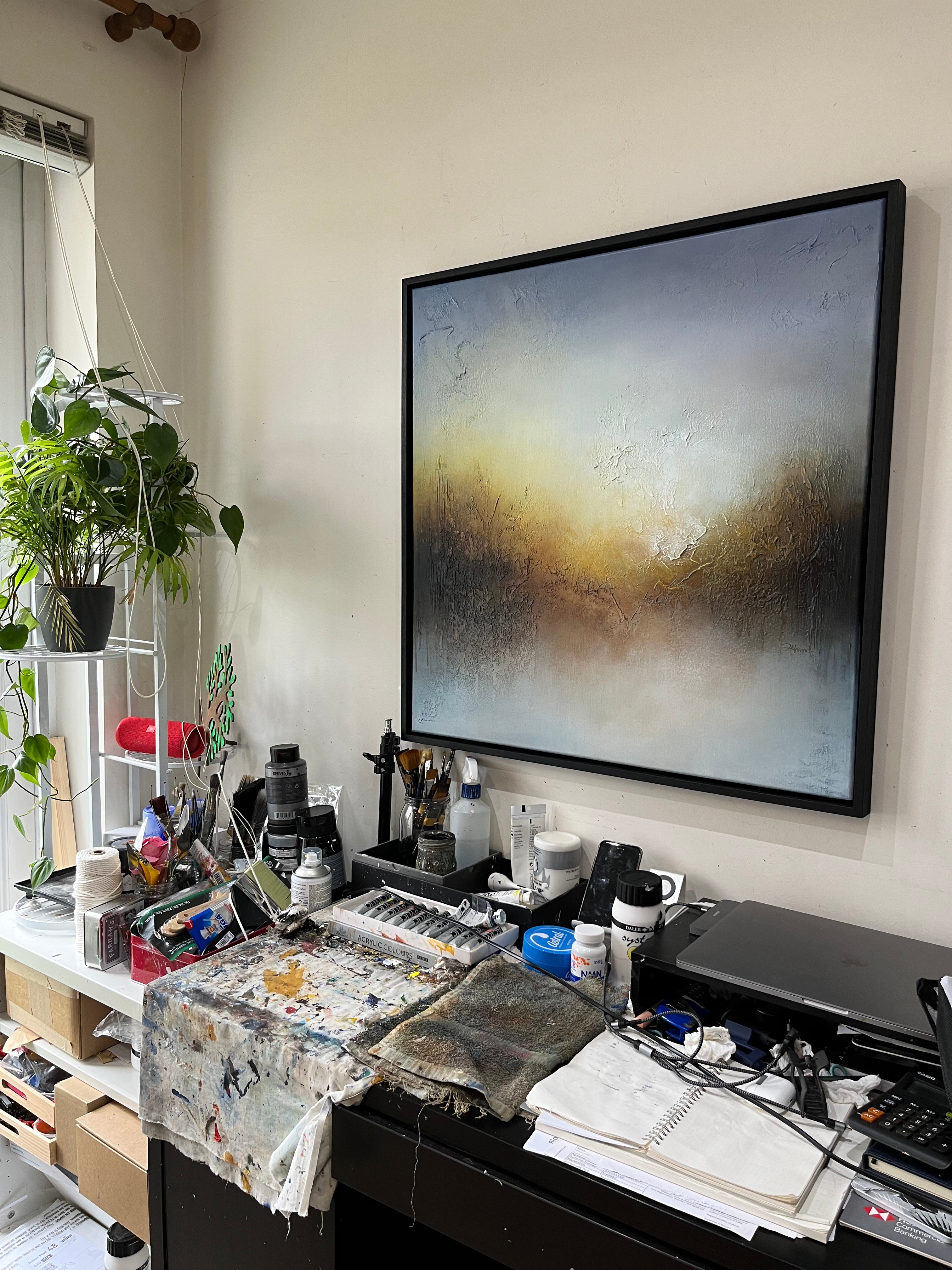 My Light framed abstract painting displayed in the artist’s studio, with grey, blue and golden-brown tones